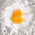 orange slice circle of fruit on sliver metallic iced background.cold white and vivid orange color.aesthetic flat lay idea food