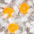 orange slice circles of fruit on sliver metallic iced background.cold white and vivid orange colors.aesthetic flat lay idea design