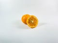 Orange slice displayed in front of a whole orange on a plain white background Royalty Free Stock Photo
