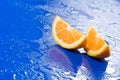 Orange slices on wet blue surface