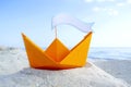 Orange Paper Boat on Sandy Seashore Close-up Small Boat from Paper on Background Royalty Free Stock Photo