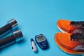 Orange sneakers, metal dumbbells and a blood glucose meter