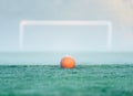 An orange soccer ball centered in front of an out of focus soccer goal