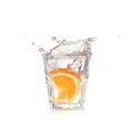 Orange splashing into glass of water on white Royalty Free Stock Photo