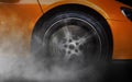 Orange Sport Car with detail on spinning and smoking wheels/tires doing burnouts Royalty Free Stock Photo