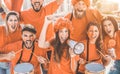 Orange sport fans screaming while supporting their team out of the stadium - Football supporters having fun at competion event - Royalty Free Stock Photo