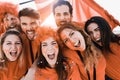 Orange sport fans screaming while supporting their team out of the stadium - Football supporters having fun at competion event - Royalty Free Stock Photo