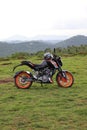 An orange sports motor bike resting on a green hill Royalty Free Stock Photo