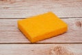 Orange square foam scouring sponge with wood background Royalty Free Stock Photo