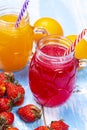 Orange and strawberry juice on blue wooden table Royalty Free Stock Photo