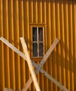 Orange structured wall with window and leant planks Royalty Free Stock Photo