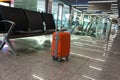 Orange suitcase in the waiting room, at the airport