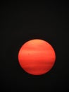 Cloud layers over orange smoky sun in black sky