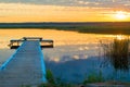 orange sun at sunset over a picturesque lake with a beautiful wooden pier