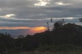 Orange sunbeam in middle of a cloudy sunset landscape viewed from a mountain