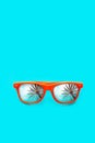 Orange sunglasses with palm tree reflections isolated in intense cyan blue background. Minimal image concept for ready for summer