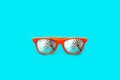 Orange sunglasses with palm tree reflections in large empty intense cyan blue background. Minimal image. Royalty Free Stock Photo