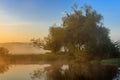 Orange sunrise with fog over river surface against blue sky. River landscape in summer morning Royalty Free Stock Photo