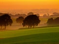 Orange sunrise over hilly farmland Royalty Free Stock Photo
