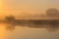 Orange sunrise over river surface with fog. River landscape in summer morning Royalty Free Stock Photo