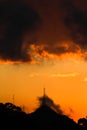 Orange sunset in cloudy sky and mountains in the background.