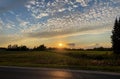 Orange Sunset countryside with a green grass field and a visible driveway to the house. Koku silhouette