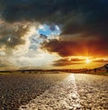 Orange sunset in dramatic clouds over asphalt road Royalty Free Stock Photo