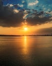 Orange sunset in dramatic clouds over water Royalty Free Stock Photo