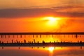 Orange sunset, dramatic and majestic sky over beach with sun reflection in water. Wood posts for salt extraction of Royalty Free Stock Photo