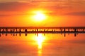 Orange sunset, dramatic and majestic sky over beach with sun reflection in water. Wood posts for salt extraction of Royalty Free Stock Photo