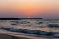 Orange sunset with golden reflections in sea waves, Al Hamriyah beach in Umm Al Quwain, UAE