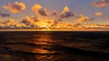 Orange sunset over Baltic sea shoreline with clouds and reflection in waves, selective focus Royalty Free Stock Photo