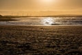 Orange sunset over Enniscrone Beach, Ireland. People are walking on a beach. Windmills in background. Green energy. Royalty Free Stock Photo