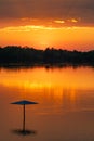 Orange sunset over a river or lake with trees on the horizon and clouds in the sky Royalty Free Stock Photo