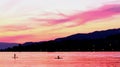 Orange sunset and Pink Sunset over a Lake with 2 paddle chilling in the middle of the picture .