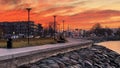 Orange sunset at promenade women sit relaxing on bench dramatic pink clouds on sea sky Baltic  Tallinn old town on horizon Royalty Free Stock Photo