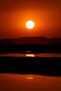 an orange sunset reflects the setting sun in the river near the road