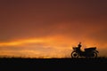 Orange sunset sky. Silhouette motorcycle in sunset landscape backdrop