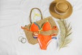 Orange swim suit, straw hat, straw bag, flip flops on white background. Summer concept, clothes for vacation, summer holidays Royalty Free Stock Photo
