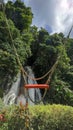 Orange swing outdoor on natural waterfall background. Empty swing object surrounded by green trees in the forest, no people Royalty Free Stock Photo