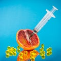 Orange, syringe, round yellow pills on blue background. Fruit citrus gelatin capsule. Vegan vitamin C. Detox treatment Royalty Free Stock Photo