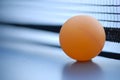 Orange table tennis ball on blue table with net Royalty Free Stock Photo