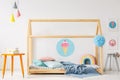 Orange table under colorful lamps next to a wooden handmade bed