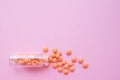 Orange tablets from glass bottle on pink background. copyspace for text. Epidemic, painkillers, healthcare, treatment pills and