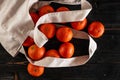 tangerine clementine friuts fall out or tip out from white shopper bag on rustic wooden table Royalty Free Stock Photo