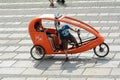 Orange taxi bike carrying passenger stopped at Reichstag.