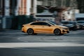 Orange taxi car is driving down a wide city street. Kia K5 sedan in motion blur Royalty Free Stock Photo