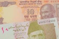 A orange ten rupee bill from India paired with a pink and grey ten rupee note from Pakistan.