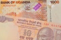 A orange ten rupee bill from India paired with a orange and white one thousand shilling bill from Uganda.