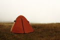Orange tent on a hill in fog Royalty Free Stock Photo